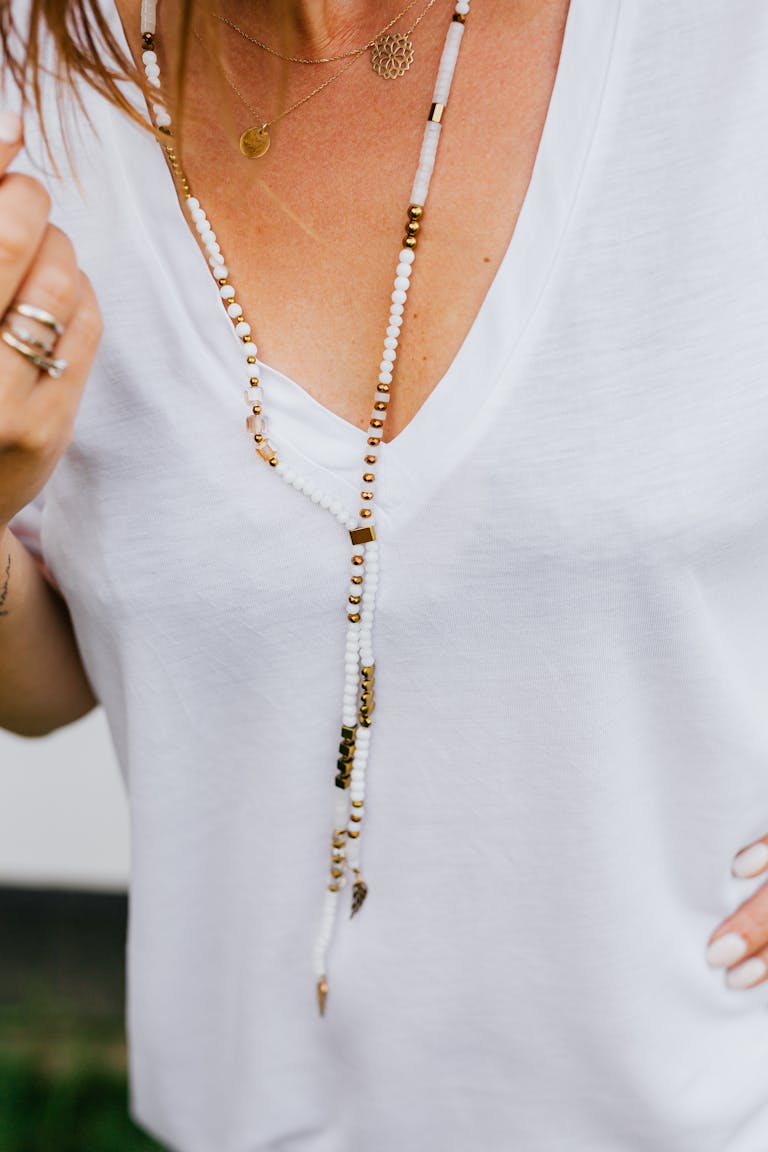 Close-up of a stylish beaded necklace worn over a simple white top, showcasing elegance.